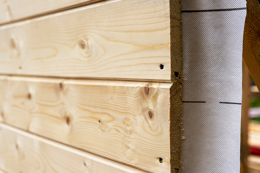 cladding of a wooden frame house with clapboard and vapor barrier. construction of houses.