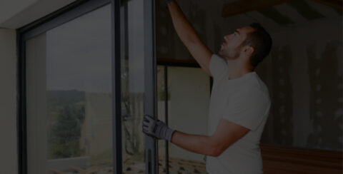 handsome young man installing bay window in a new house construction site